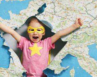 Illustration montrant une petite fille de dos, déguisée en super-héroïne avec une cape jaune et un loup. Elle se tient debout, les bras levés montrant ses muscles, devant une immense carte de France détaillée. L'image symbolise la force et l'avenir des territoires.