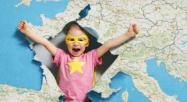 Illustration montrant une petite fille de dos, déguisée en super-héroïne avec une cape jaune et un loup. Elle se tient debout, les bras levés montrant ses muscles, devant une immense carte de France détaillée. L'image symbolise la force et l'avenir des territoires.